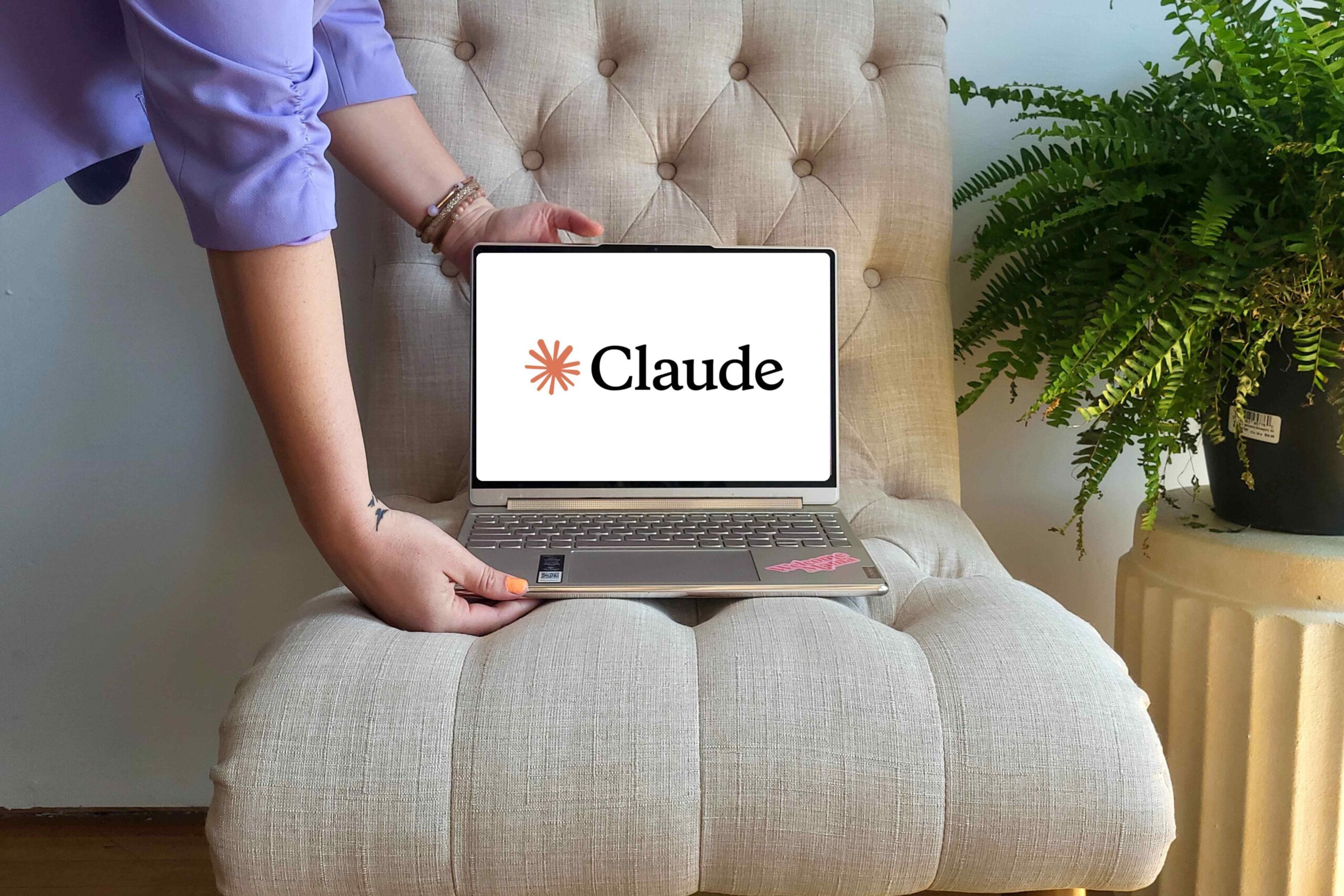Laptop showing the Claude logo on a tufted chair, the AI tool Julie used to build her task hub