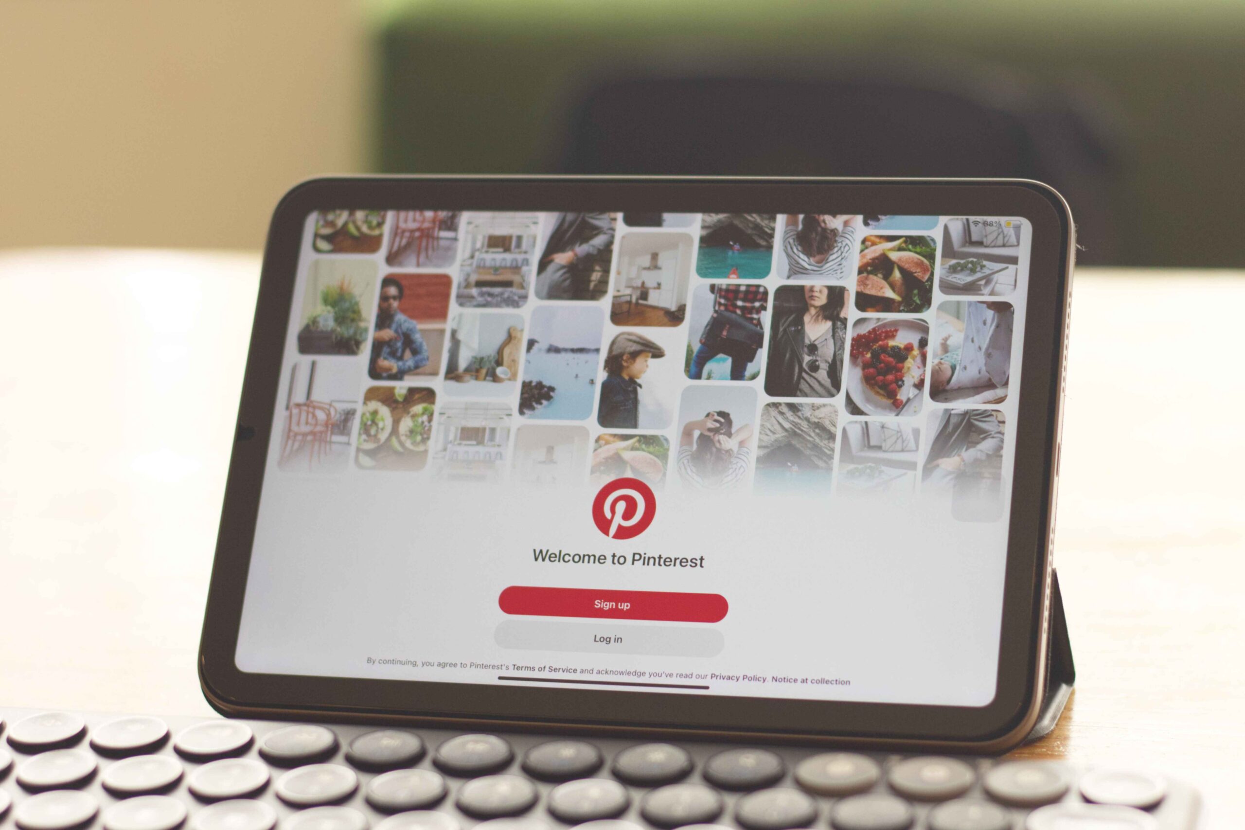 Pinterest management: tablet on a desk showing the Pinterest welcome screen with sign up and log in buttons
